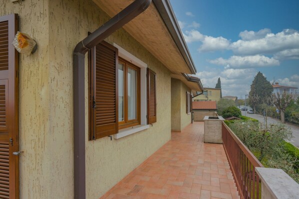 A building with a balcony, wooden shutters, and a tiled floor.
