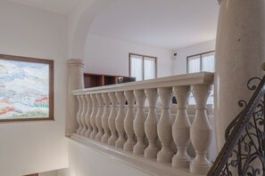 Een trap met een balustrade, een schilderij aan de muur en een raam met gordijnen.