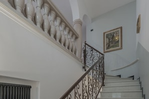 A staircase with a balustrade, a framed picture on the wall, and a radiator on the wall.