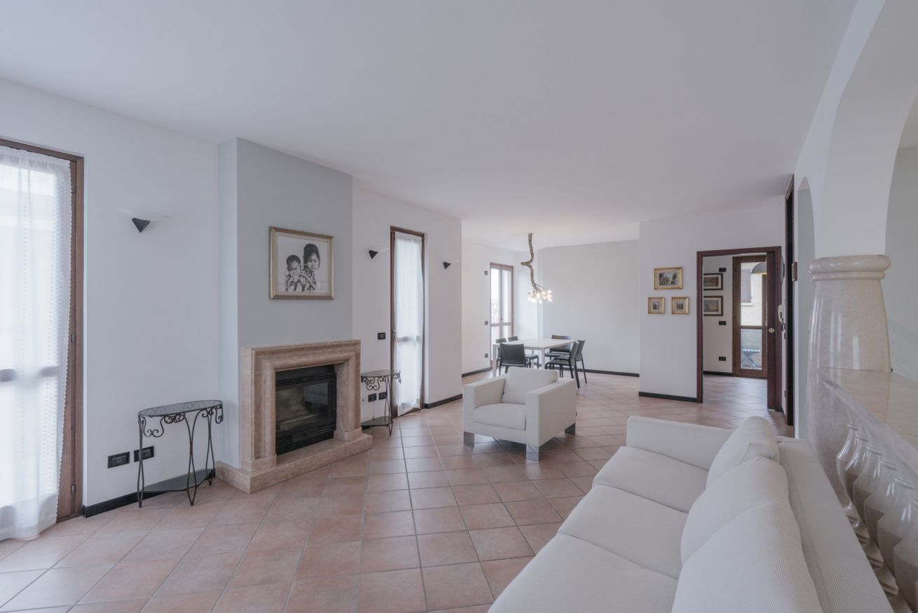 Un salon spacieux doté d’une cheminée, d’un canapé blanc et d’un coin repas avec une table et des chaises.