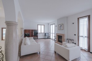A spacious living room with a fireplace, two white sofas, a television, and a bookshelf. - MARY THREE HOUSE - penthouse with terrace 2 steps from the lake (Sirmione)