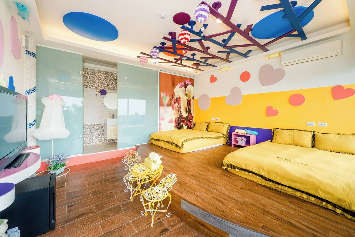 A modern bedroom with a yellow bed, a TV, and a unique ceiling design.