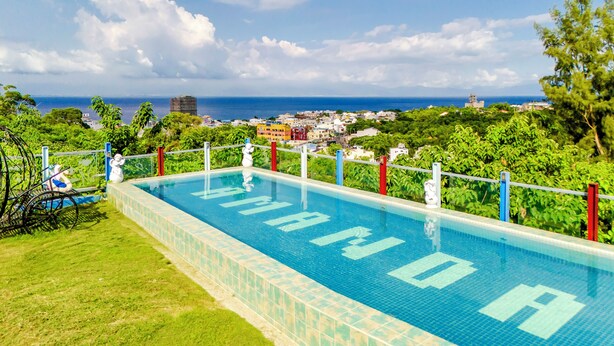 A swimming pool with a view of the ocean and cityscape. - Happiness Pink B&B (Liuqiu)
