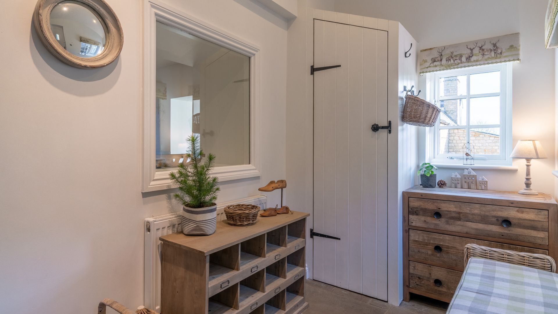 A cozy room with a wooden console table, a mirror, a door, and a window with a view.