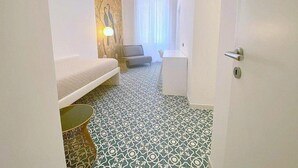 Ein Hotelzimmer mit Bett, kleinem Schreibtisch, einer Couch und einem gemusterten Boden.