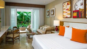 Ein Hotelzimmer mit einem Bett, einer Couch, einem Schreibtisch und einem Stuhl. Vorhänge und ein Fenster mit Blick auf Grünflächen.