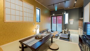 Une pièce de style japonais traditionnel, avec un sol recouvert de tatamis, une petite table basse accompagnée d’un service à thé et des portes coulissantes.