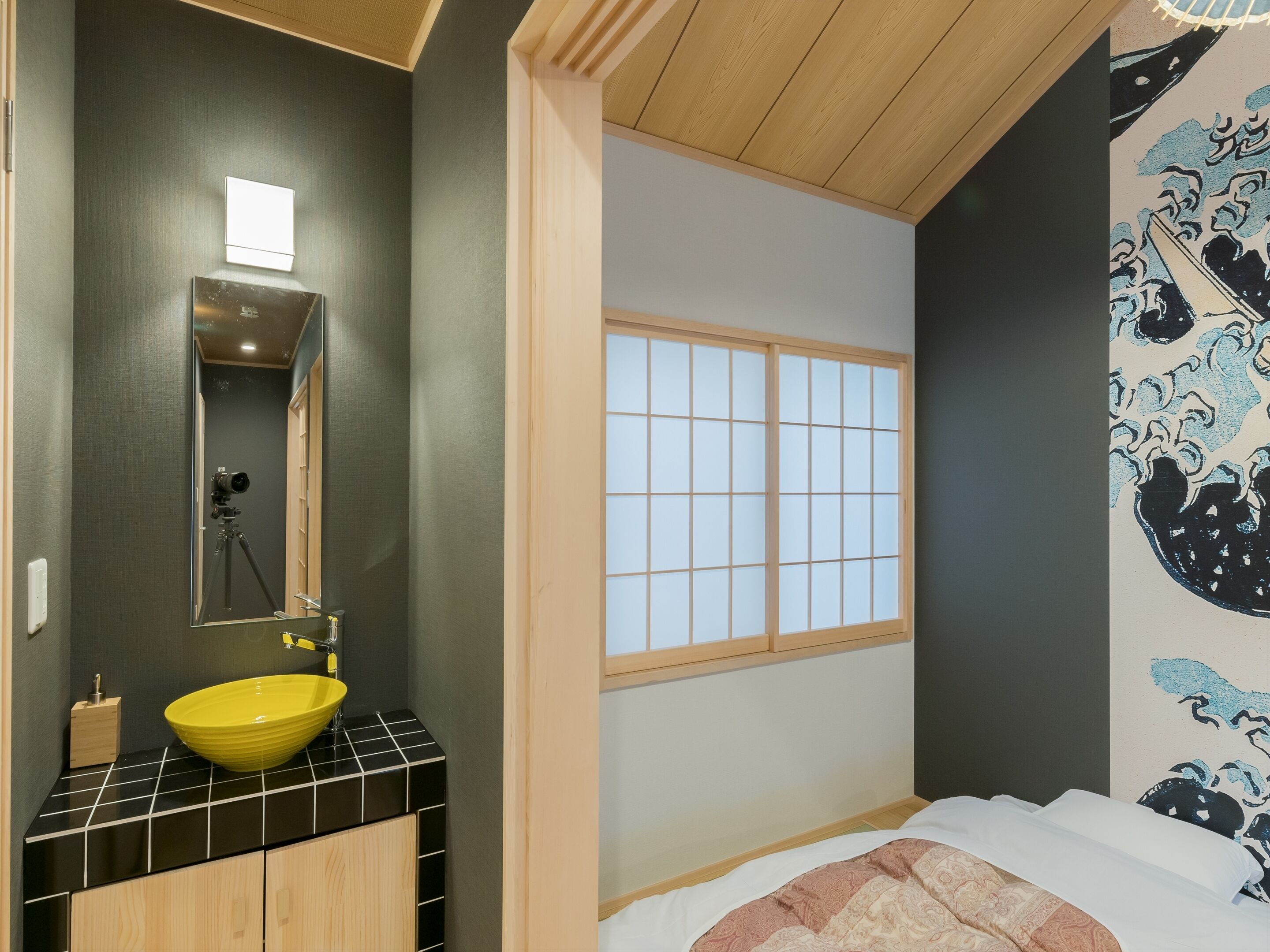 A modern bathroom with a yellow sink, a mirror, and a tripod.