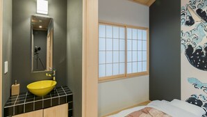 Une salle de bain moderne avec un lavabo jaune, un miroir et un trépied.