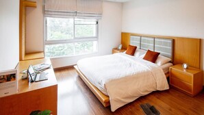 A bedroom with a bed, bedside tables, a desk with a laptop, and a window with blinds. - Lake Side Condominium (Khon Kaen)