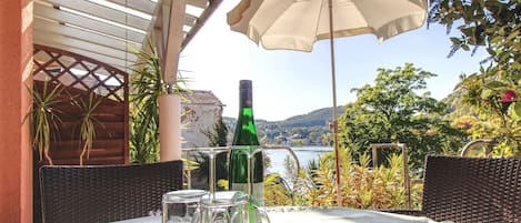 A table set outdoors with a bottle and glasses, surrounded by wicker chairs, under a canopy.