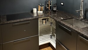 Una cocina moderna con armarios oscuros, un lavamanos de acero inoxidable y una lámpara colgante roja llamativa.