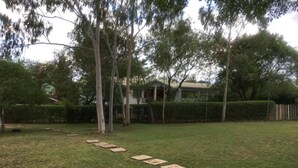 A grassy backyard with a stone pathway leading to a house. - Hotel Hippo Buck (Homa Bay)