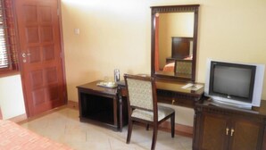 A hotel room with a bed, a desk with a chair, a television, and a mirror. - Hotel Hippo Buck (Homa Bay)
