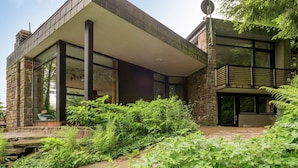 Una casa moderna con fachada de piedra, ventanas amplias y un patio cubierto.
