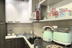 A modern kitchen with a gas stove, two vintage-style toasters, a kettle, and a sink. - IL MONDO DI CLAIRE-cozy and charm (Siena)