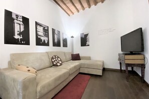 A living room with a beige sofa, a red rug, and a flat-screen TV on a wooden stand. - IL MONDO DI CLAIRE-cozy and charm (Siena)