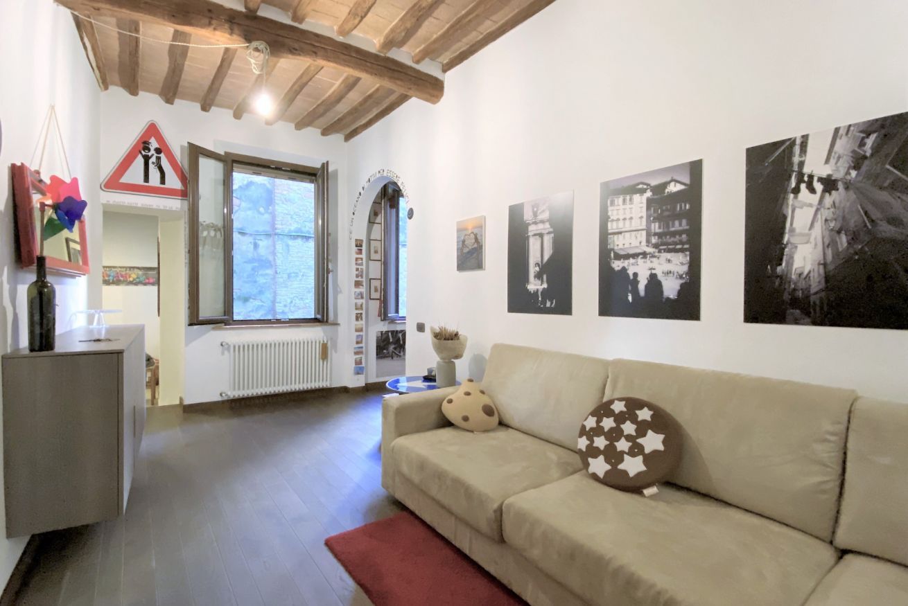 Un salon avec un canapé, un radiateur, une fenêtre et des tableaux accrochés au mur.