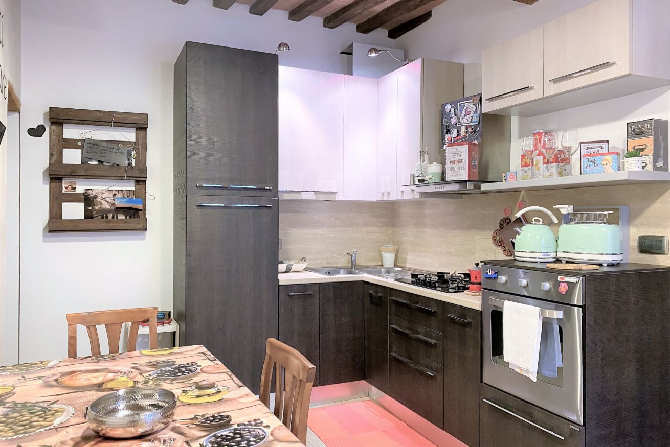Une cuisine compacte avec des meubles de couleur sombre, un four en acier inoxydable et une table à manger dressée avec des assiettes et des bols.
