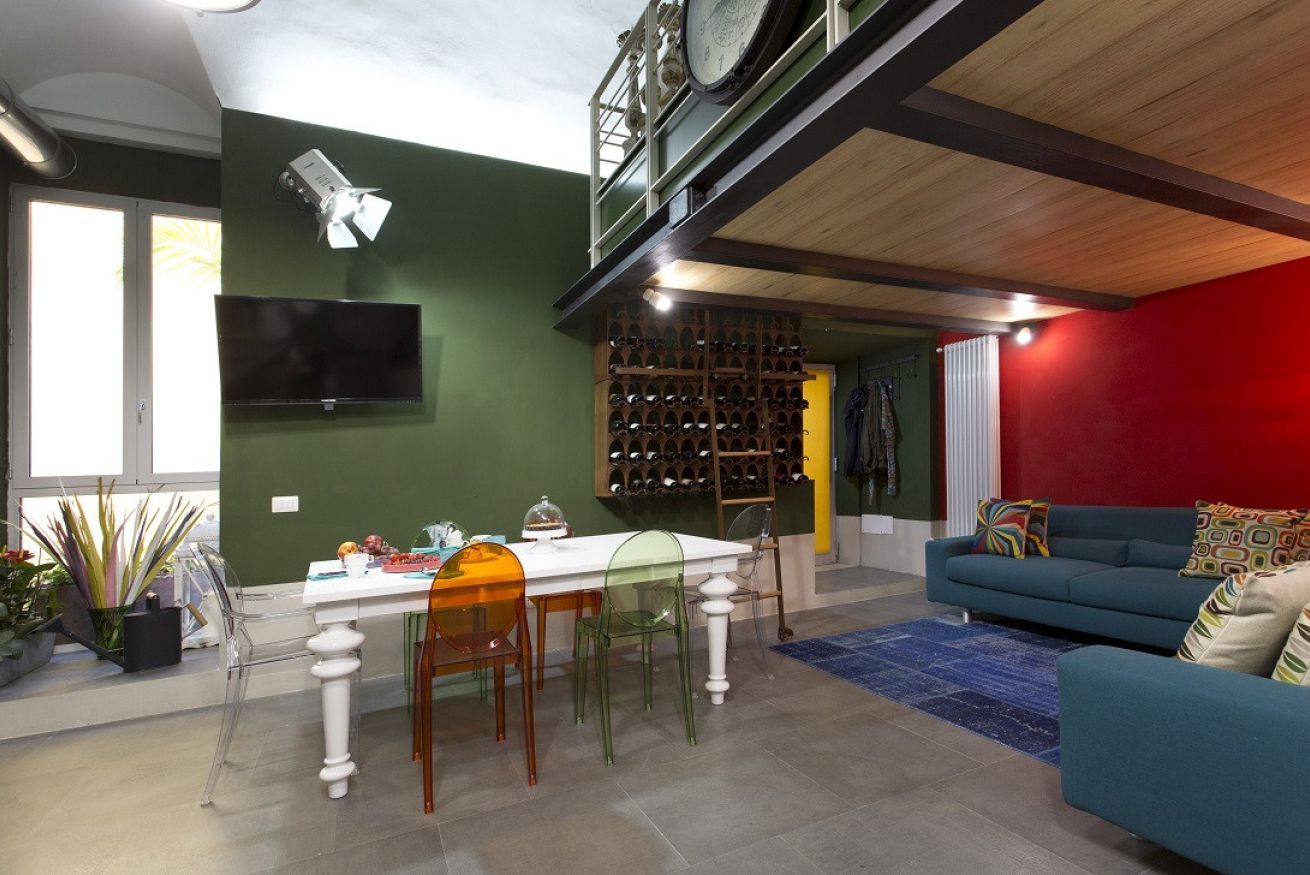 Zona pranzo con tavolo e sedie, una dispensa per vini e un televisore appeso al muro.