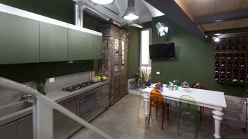 Una cocina moderna con armarios verdes, un aparador de madera, una mesa de comedor con sillas y una vinoteca.
