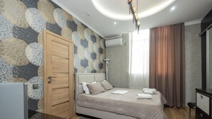 A bedroom with a bed, a wardrobe, a desk, and a mirror. - Iris Hotel (Chisinau)