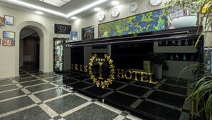 A hotel reception area with a checkered floor, a large reception desk, and a wall clock. - Iris Hotel (Chisinau)