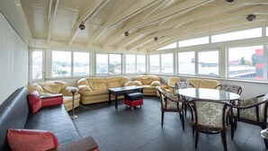A spacious lounge area with a high ceiling, large windows, and a mix of seating options including sofas and chairs. - Iris Hotel (Chisinau)