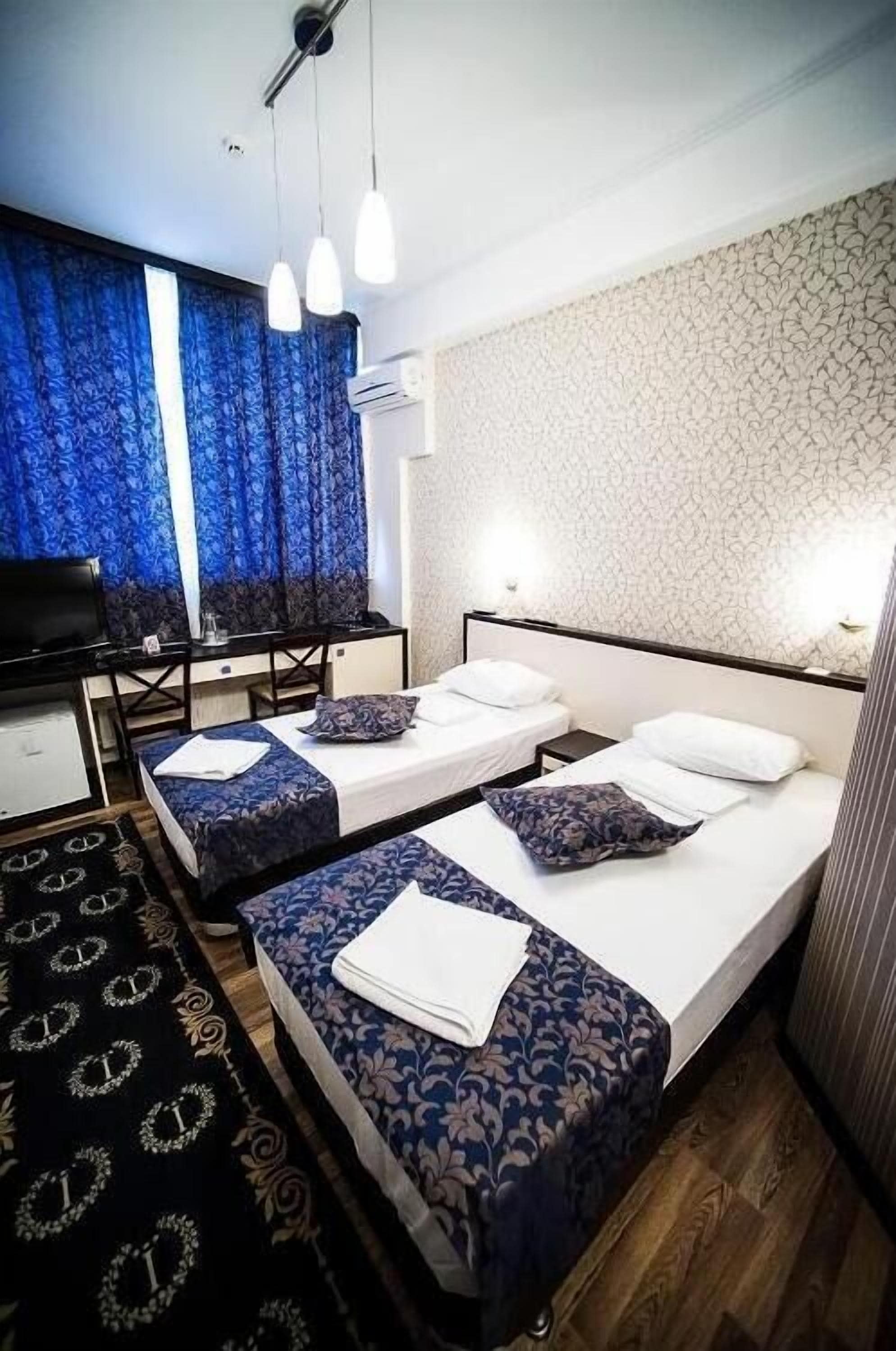Une chambre d’hôtel avec deux lits, un bureau et une télévision.