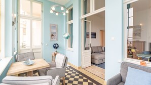 Une pièce avec un sol à carreaux, une table à manger avec des chaises, un canapé et une grande fenêtre.