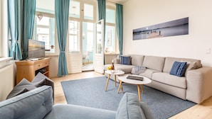 Un salon moderne avec un canapé, une table basse et un téléviseur posé sur un meuble en bois.