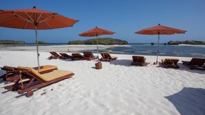 Uma praia com espreguiçadeiras e guarda-sóis vermelhos.