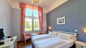 A bedroom with a bed, a chair, a desk, and a window with curtains. - Double room castle country side - Seehotel Schloss Klink (Klink)