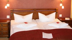 Habitación de hotel con cama doble, dos lámparas de noche, cabecero de madera y un cuadro en la pared.