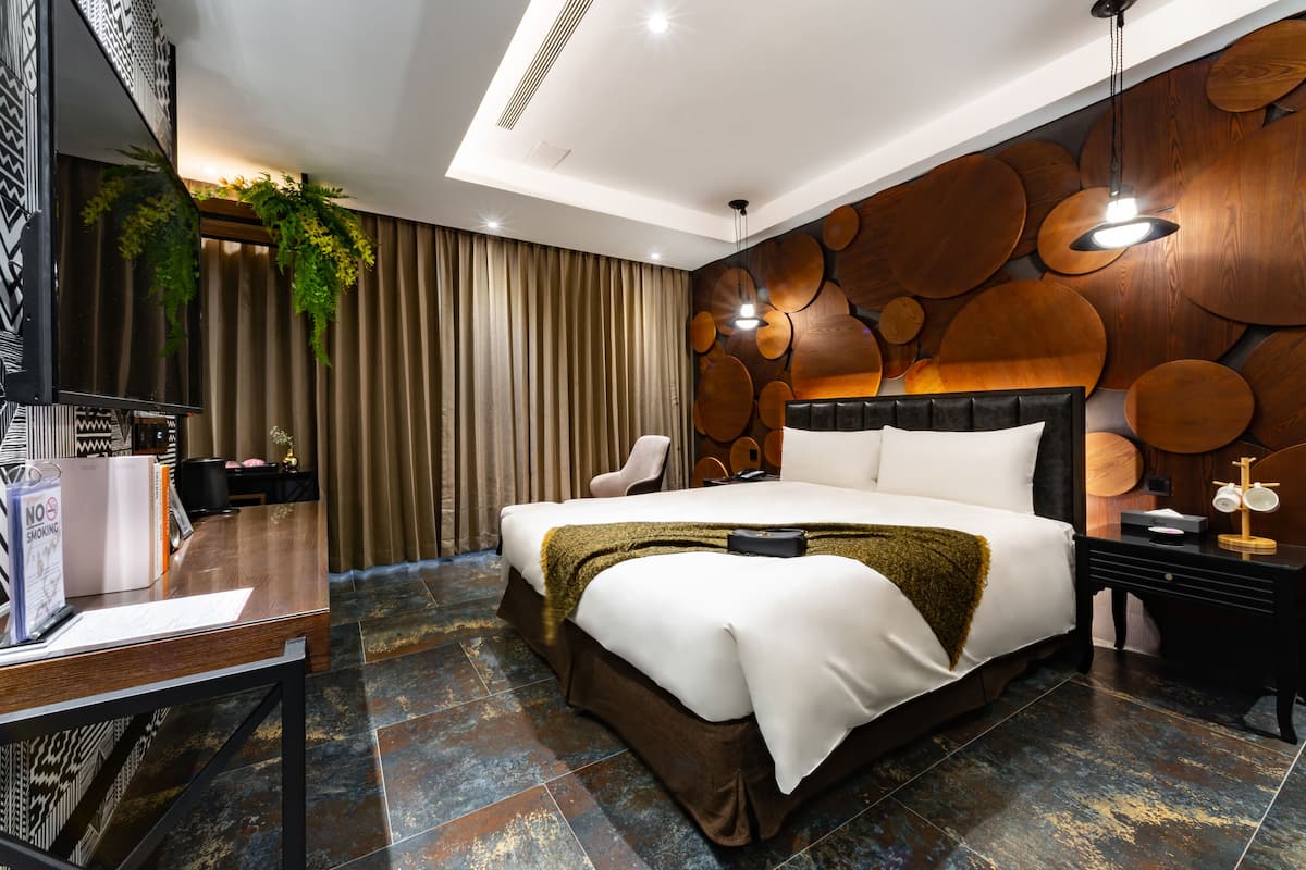 Una habitación de hotel moderna con una cama grande, un escritorio con computadora y una pared con paneles de madera redonda.