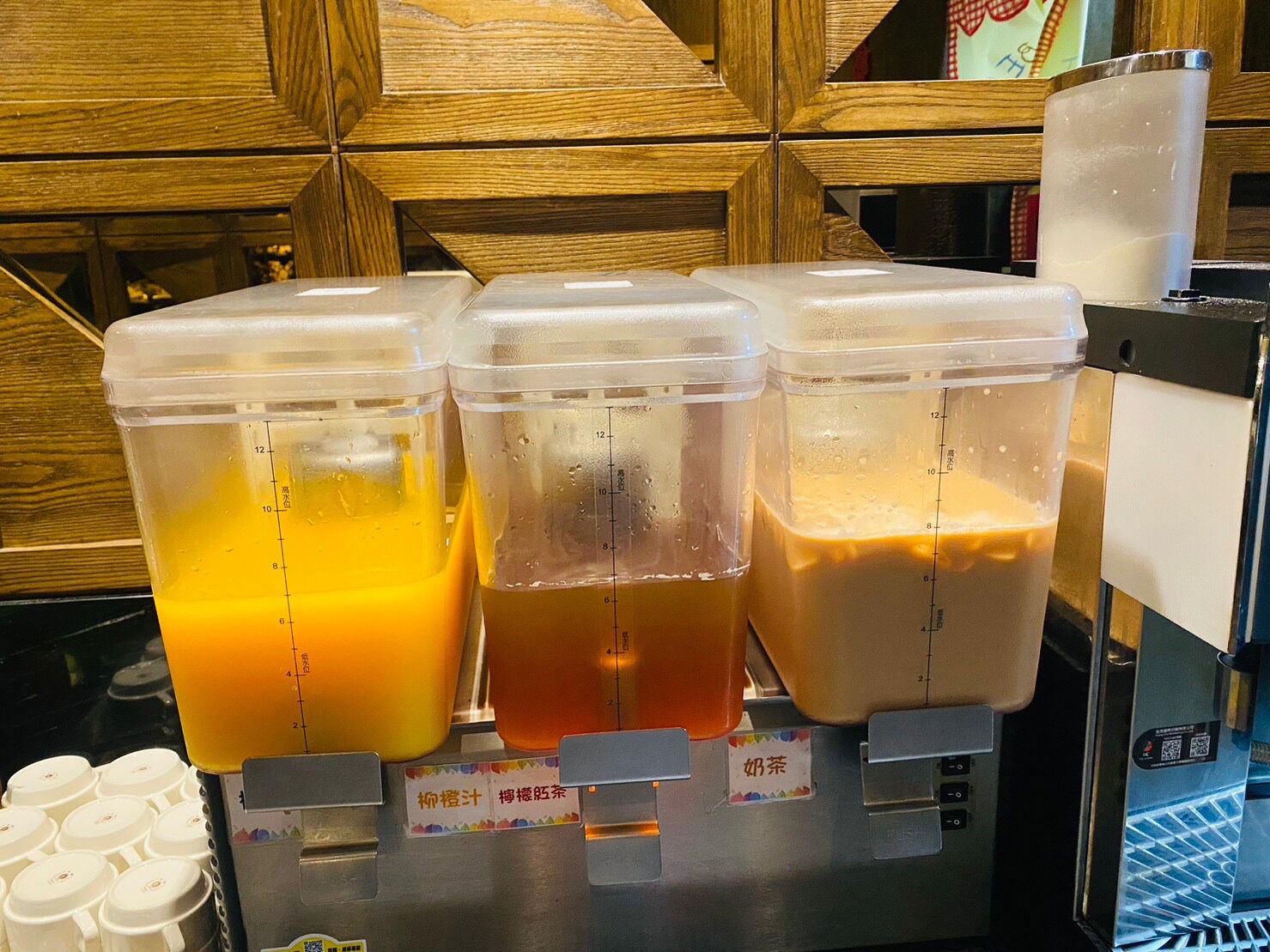 Un dispensador de bebidas con tres recipientes llenos de líquidos de diferentes colores, cada uno con indicadores de nivel.
