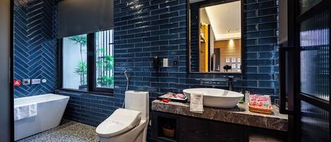 Un baño moderno con una bañera independiente, inodoro y tocador con un espejo grande.