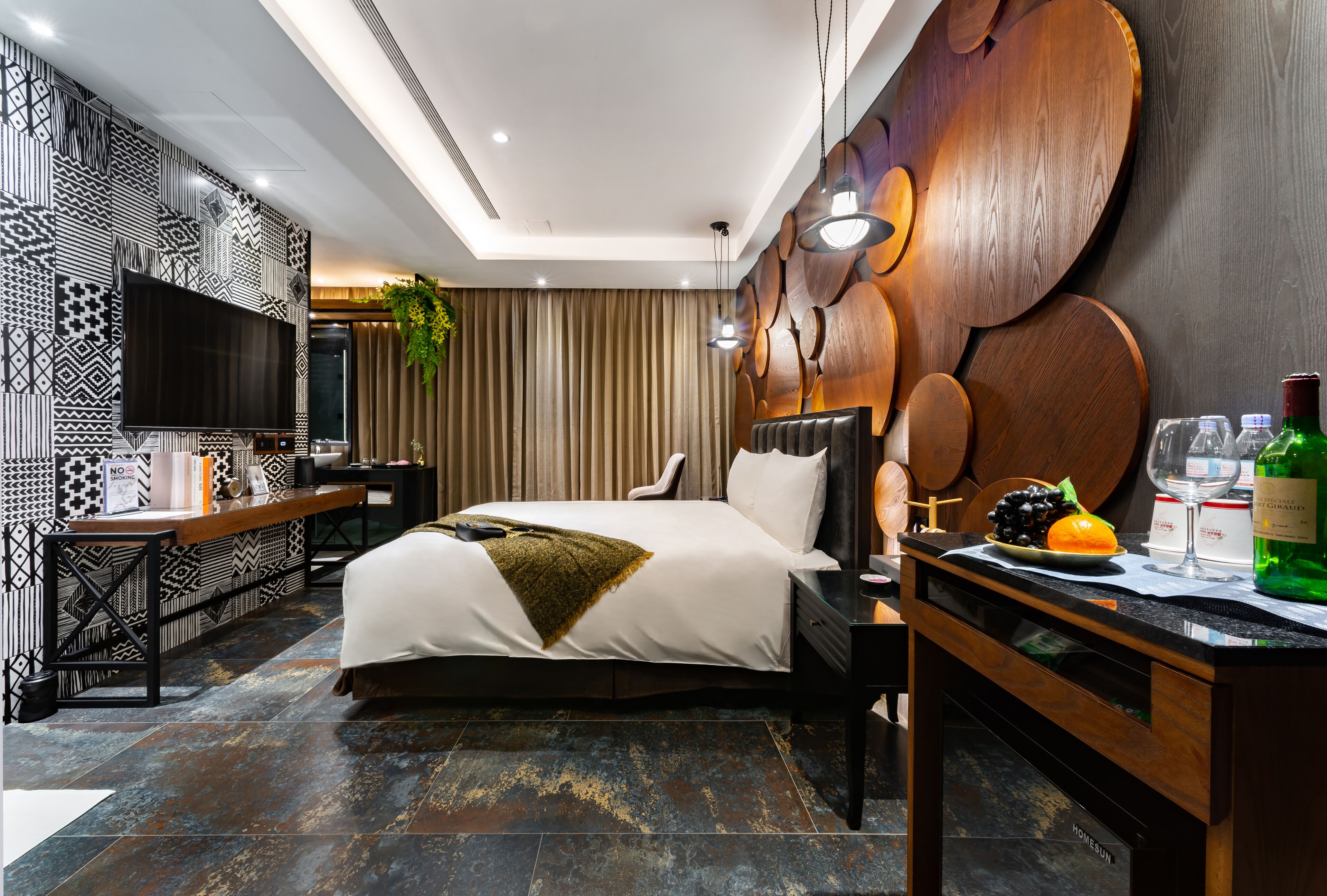 Una habitación de hotel moderna con una cama grande, un escritorio, un televisor de pantalla plana y un adorno mural.