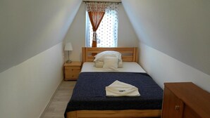 A small, neatly arranged bedroom with a single bed, a nightstand, a dresser, and a window with curtains. - Bungalow in Kolczewo with parking space (Kolczewo)