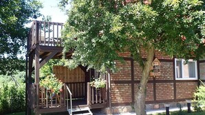 A rustic wooden cabin with a wooden deck and a small staircase leading to a loft area. - Bungalow in Kolczewo with parking space (Kolczewo)
