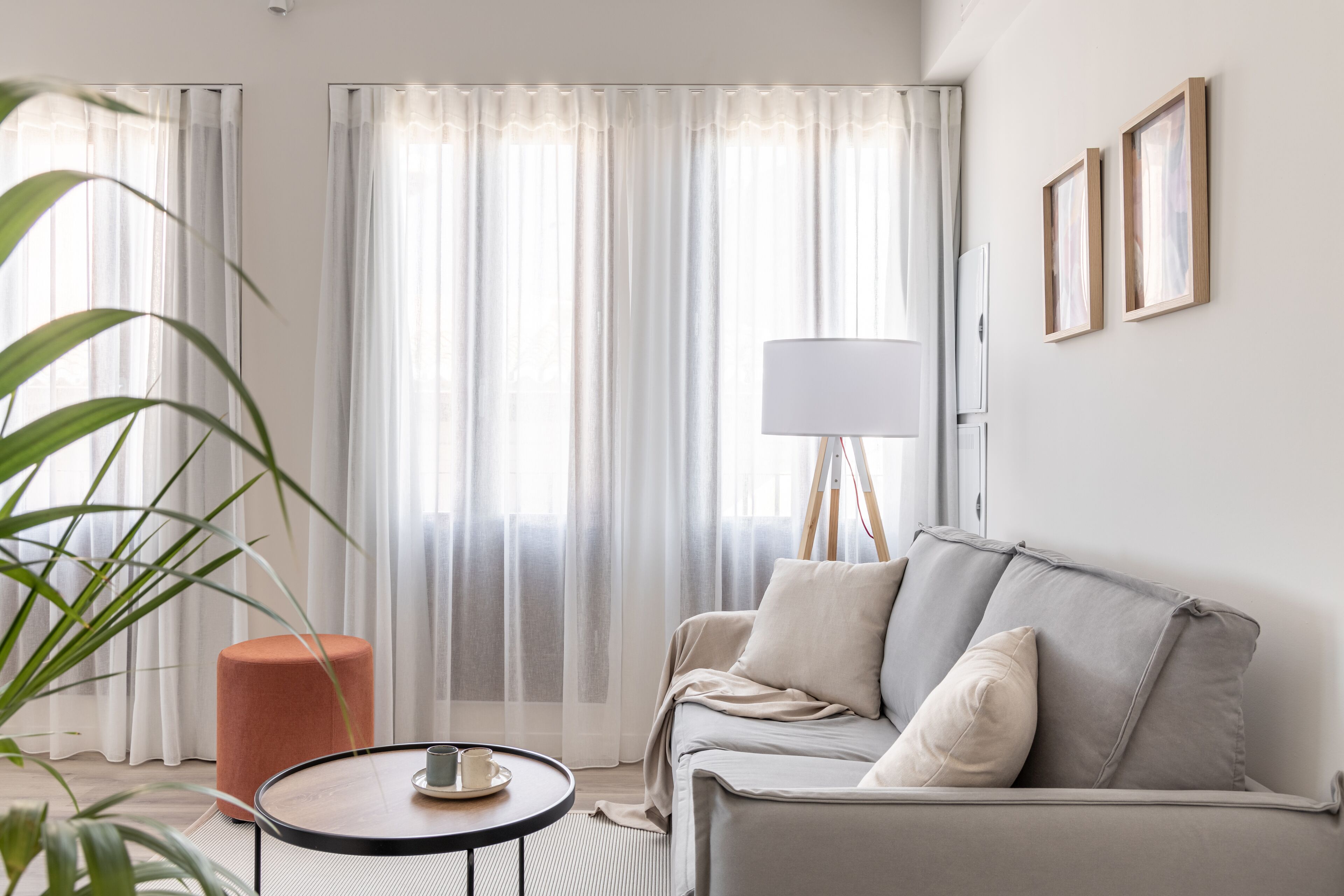 Una sala de estar moderna con un sofá gris, una mesa redonda y una lámpara de pie alta.