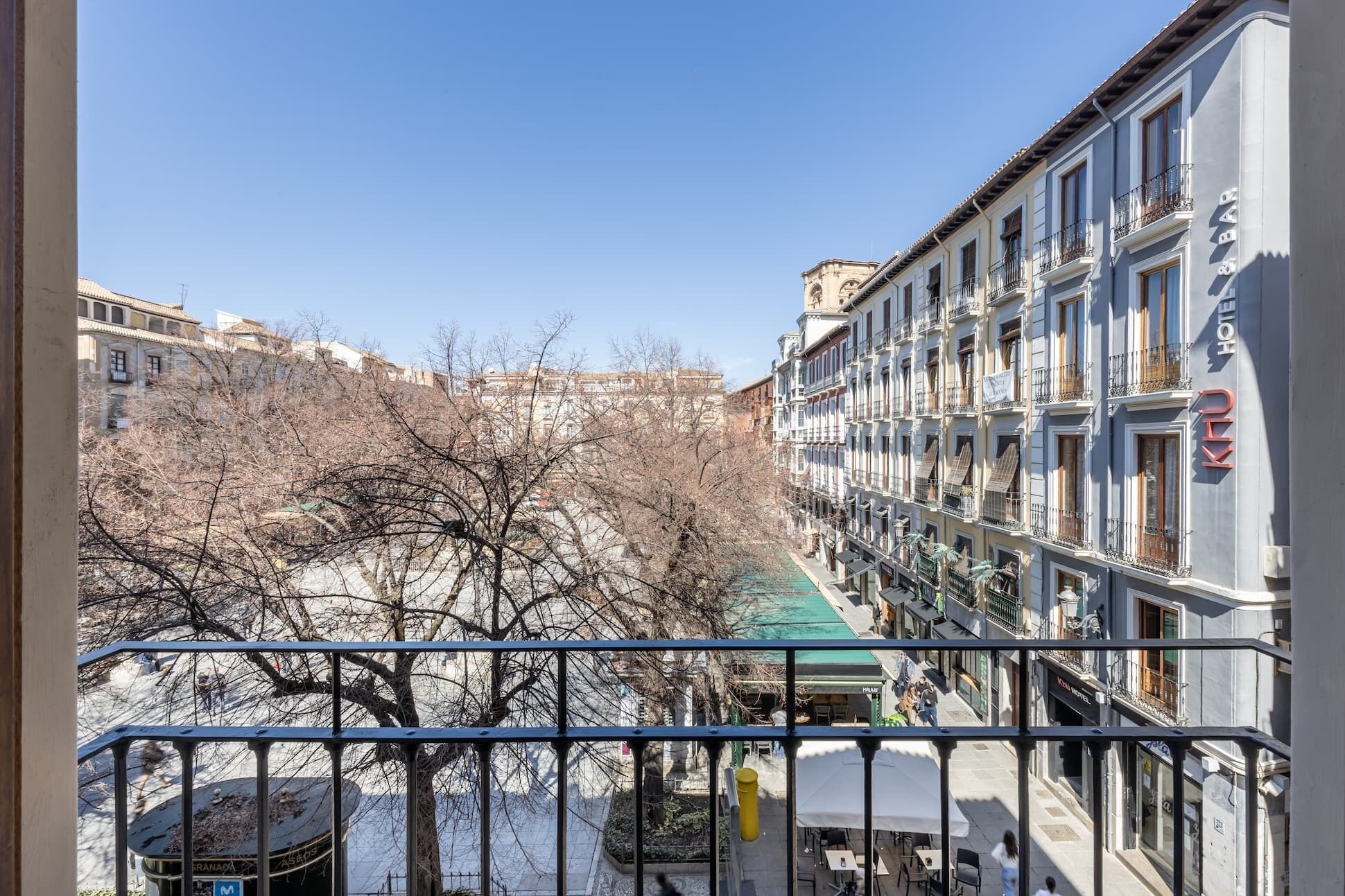 A hotel with multiple floors, balconies, and a view of a snowy street with leafless trees.
