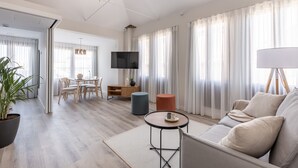 Una sala de estar moderna con un sofá, una mesa de centro, un televisor y un comedor con sillas y una mesa.