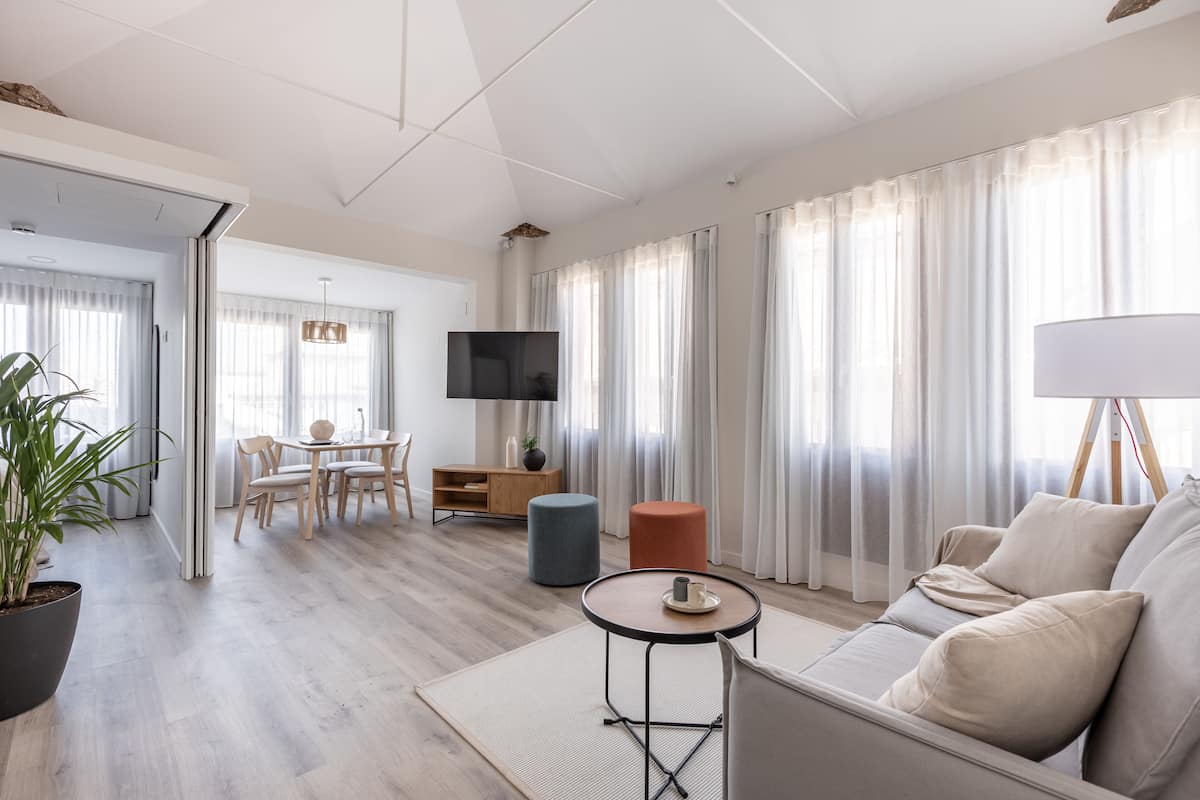 Una sala de estar moderna con un sofá, una mesa de centro, un televisor y un comedor con sillas y una mesa.