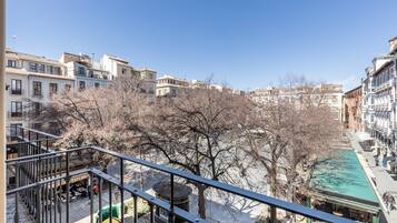 Un balcon donnant sur une rue bordée d’arbres et sur des immeubles.