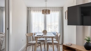 Un comedor moderno con una mesa, sillas y un televisor en la pared.