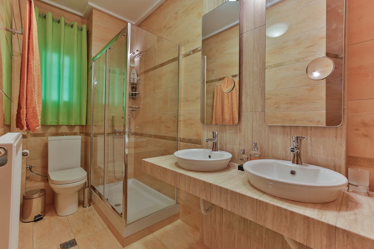 Un baño con dos lavamanos, un inodoro, una ducha y un espejo grande.