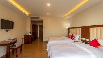 A hotel room with two beds, a desk with a chair, a television, and a kitchenette area.