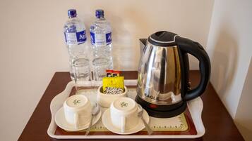 A tray with two water bottles, a coffee pot, and two cups with spoons on a table.