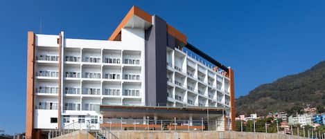 A multi-story hotel with balconies, a central staircase, and a view of the surrounding area.